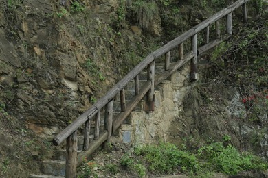 Wooden hand railings near stone stairs and plants outdoors