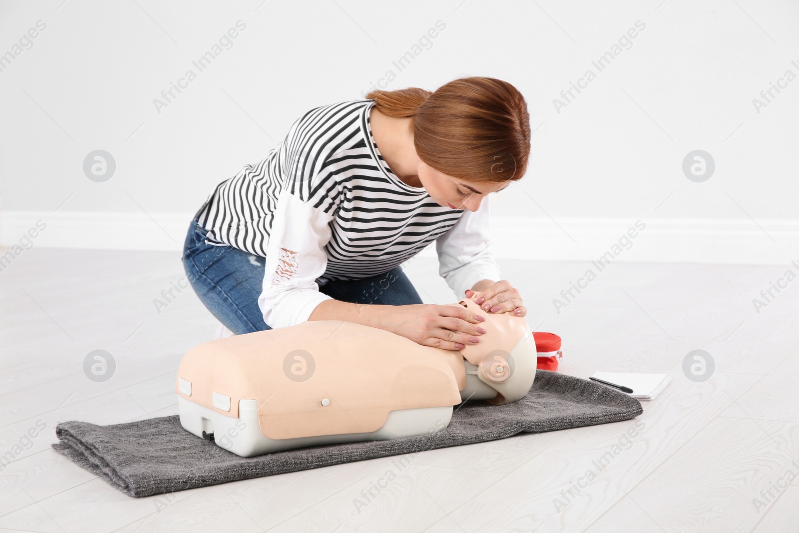 Photo of Woman practicing first aid on mannequin indoors