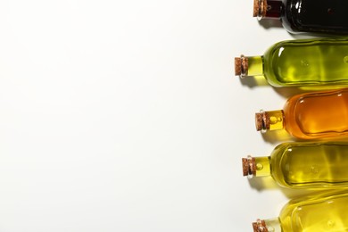 Vegetable fats. Different cooking oils in glass bottles on white background, flat lay. Space for text