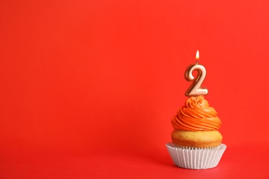 Birthday cupcake with number two candle on red background, space for text