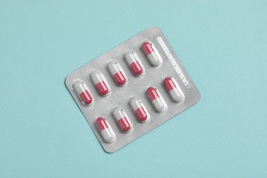 Photo of Pills in blister on turquoise background, top view