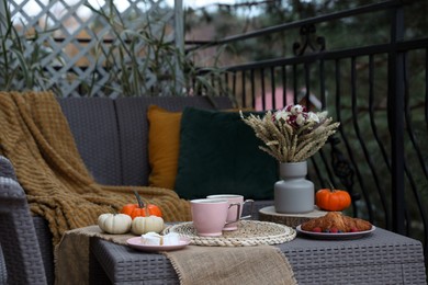 Photo of Rest on terrace with rattan furniture. Drink, dessert and autumn decor on table
