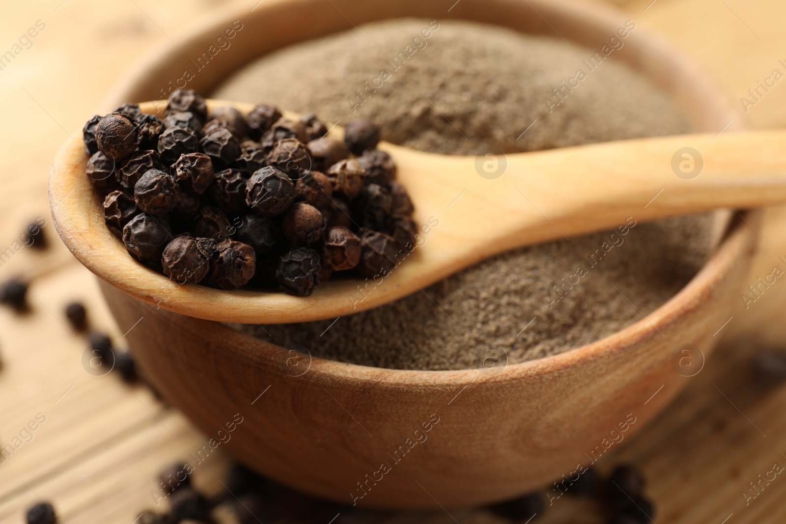 Photo of Aromatic spice. Ground and whole black pepper on wooden table, closeup