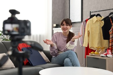 Smiling fashion blogger explaining something while recording video at home