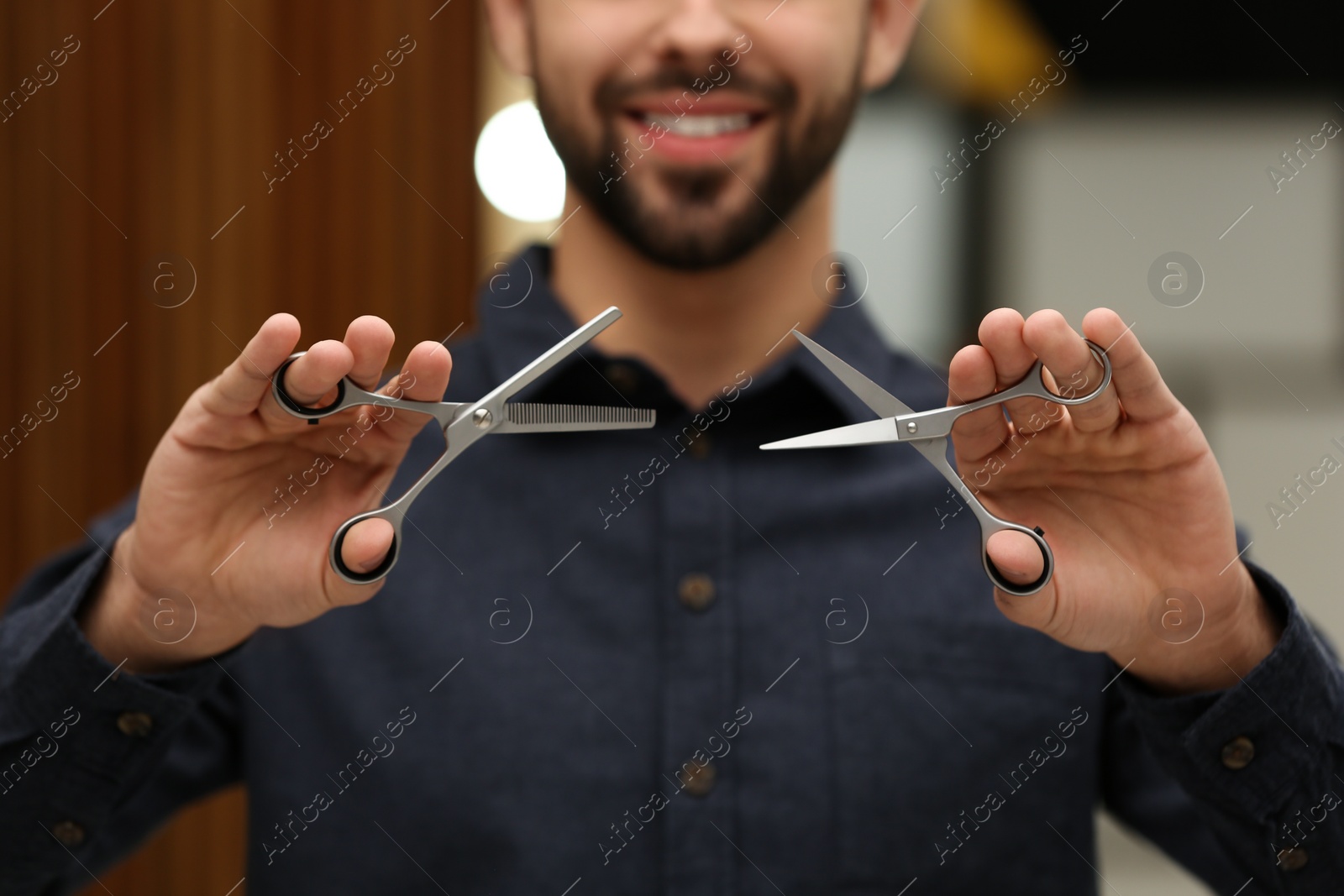 Photo of Hairstylist holding professional scissors in beauty salon, closeup