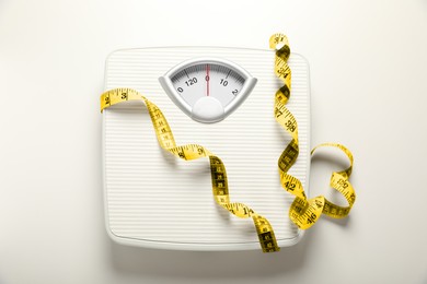Scales and measuring tape on white background, top view