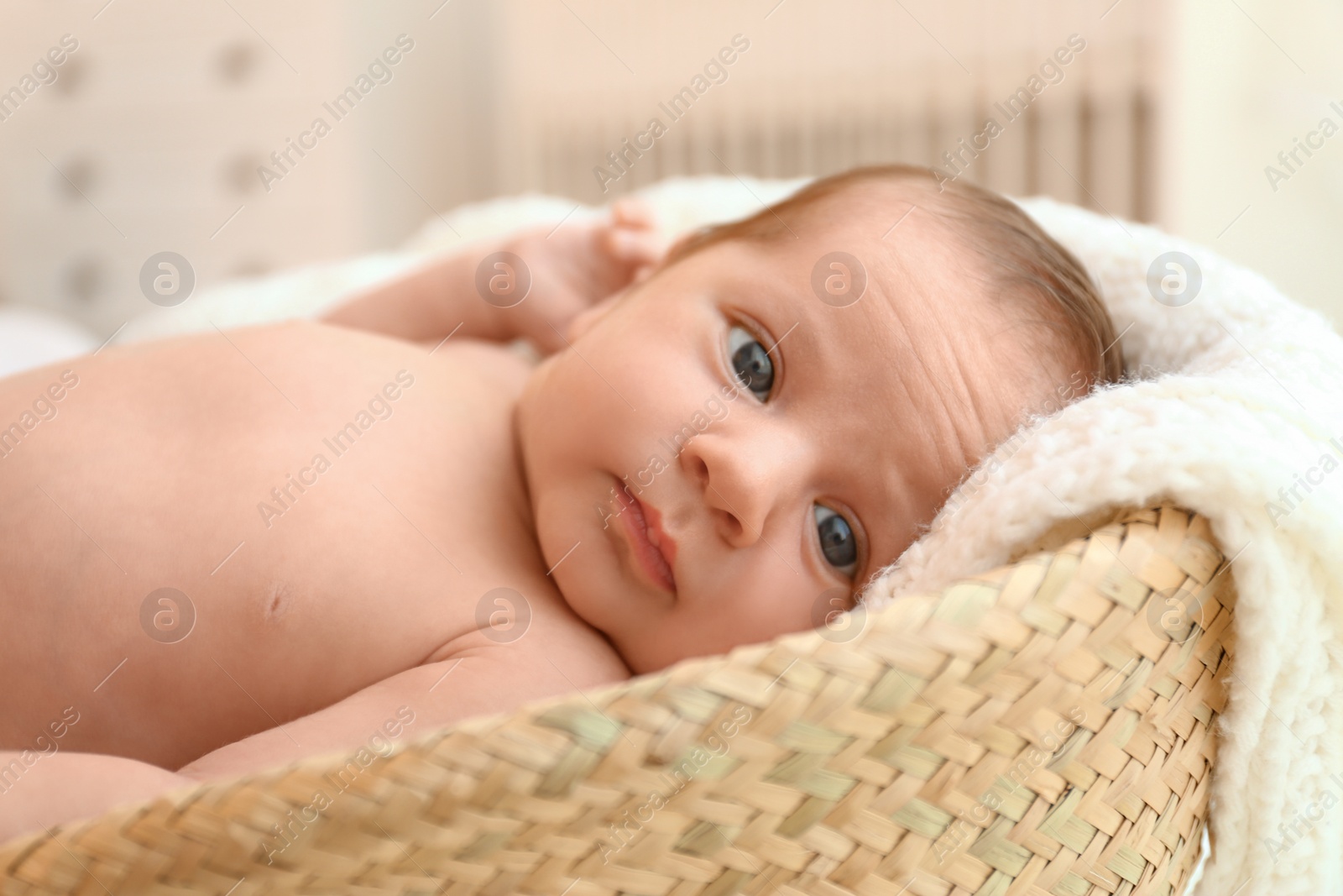 Photo of Cute little baby lying on knitted plaid in cradle