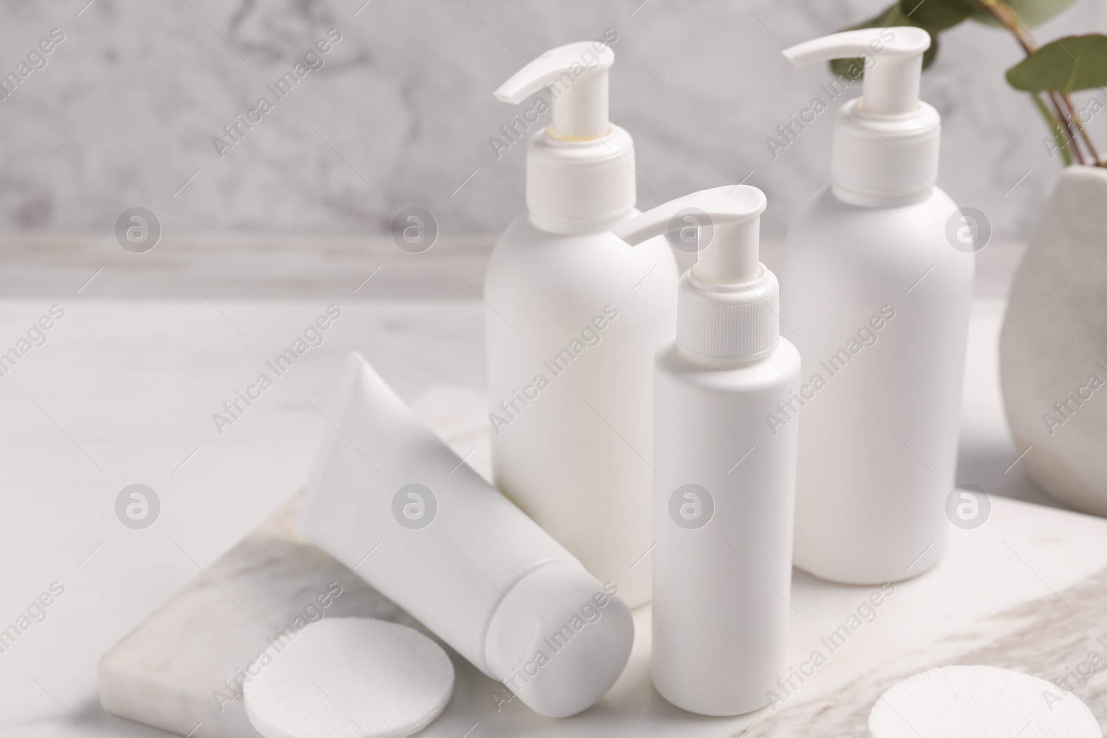 Photo of Different face cleansing products and cotton pads on white table