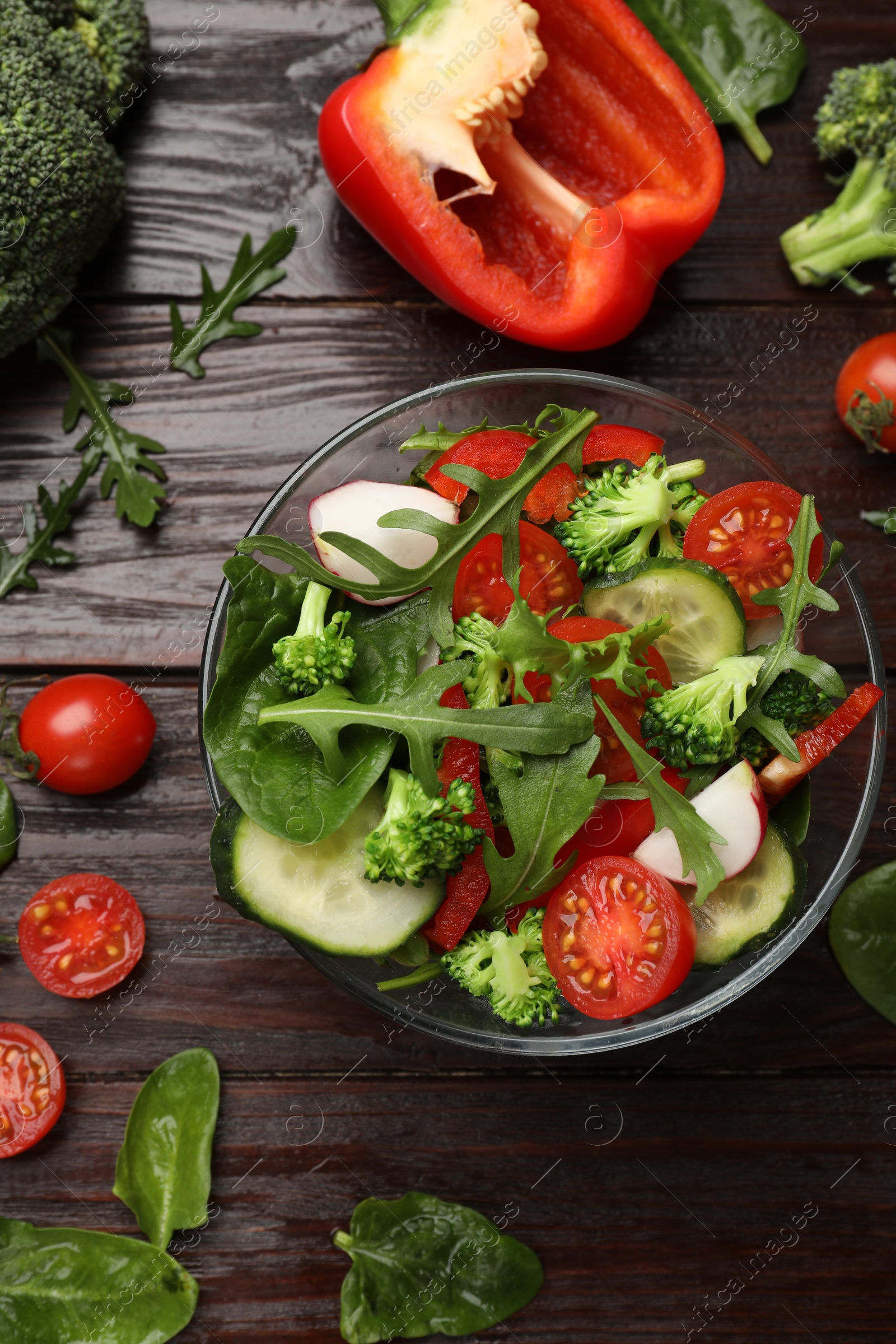 Photo of Tasty fresh vegetarian salad on dark wooden table, flat lay