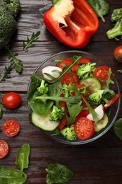 Photo of Tasty fresh vegetarian salad on dark wooden table, flat lay