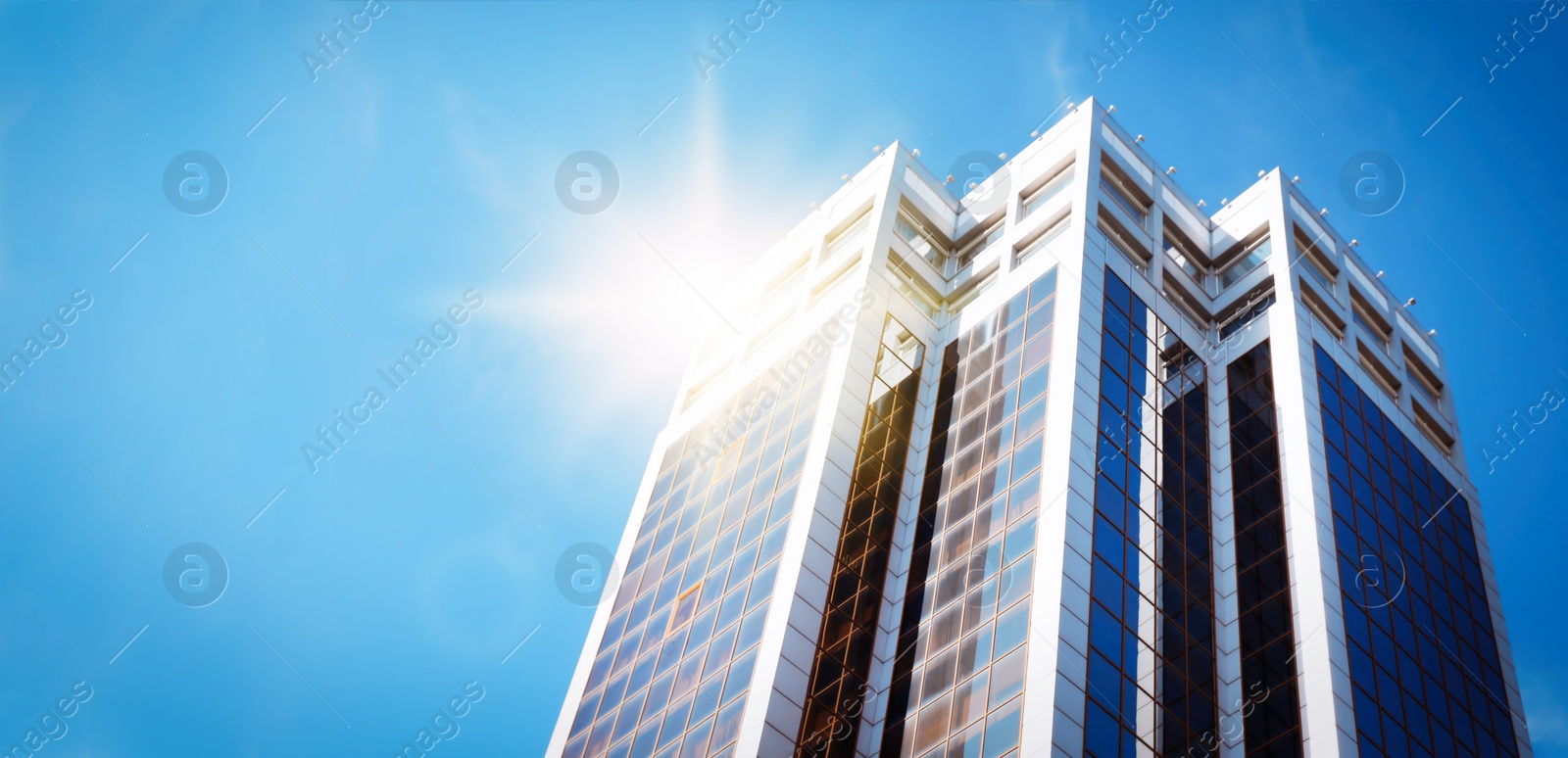 Image of Modern skyscraper with tinted windows against blue sky, low angle view. Building corporation