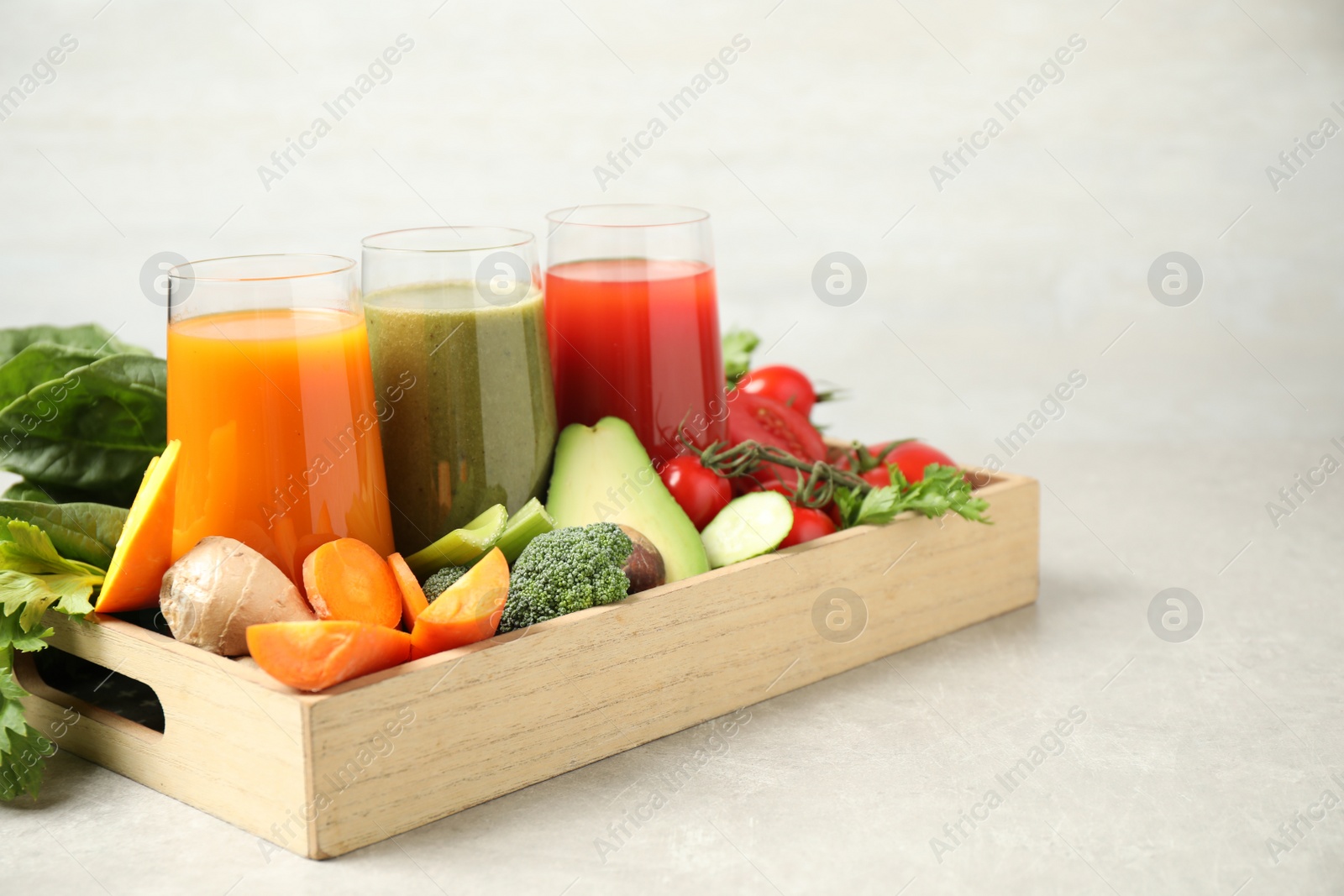 Photo of Delicious vegetable juices and fresh ingredients on light grey table