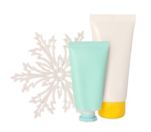 Photo of Tubes of hand cream and snowflake isolated on white. Winter skin care