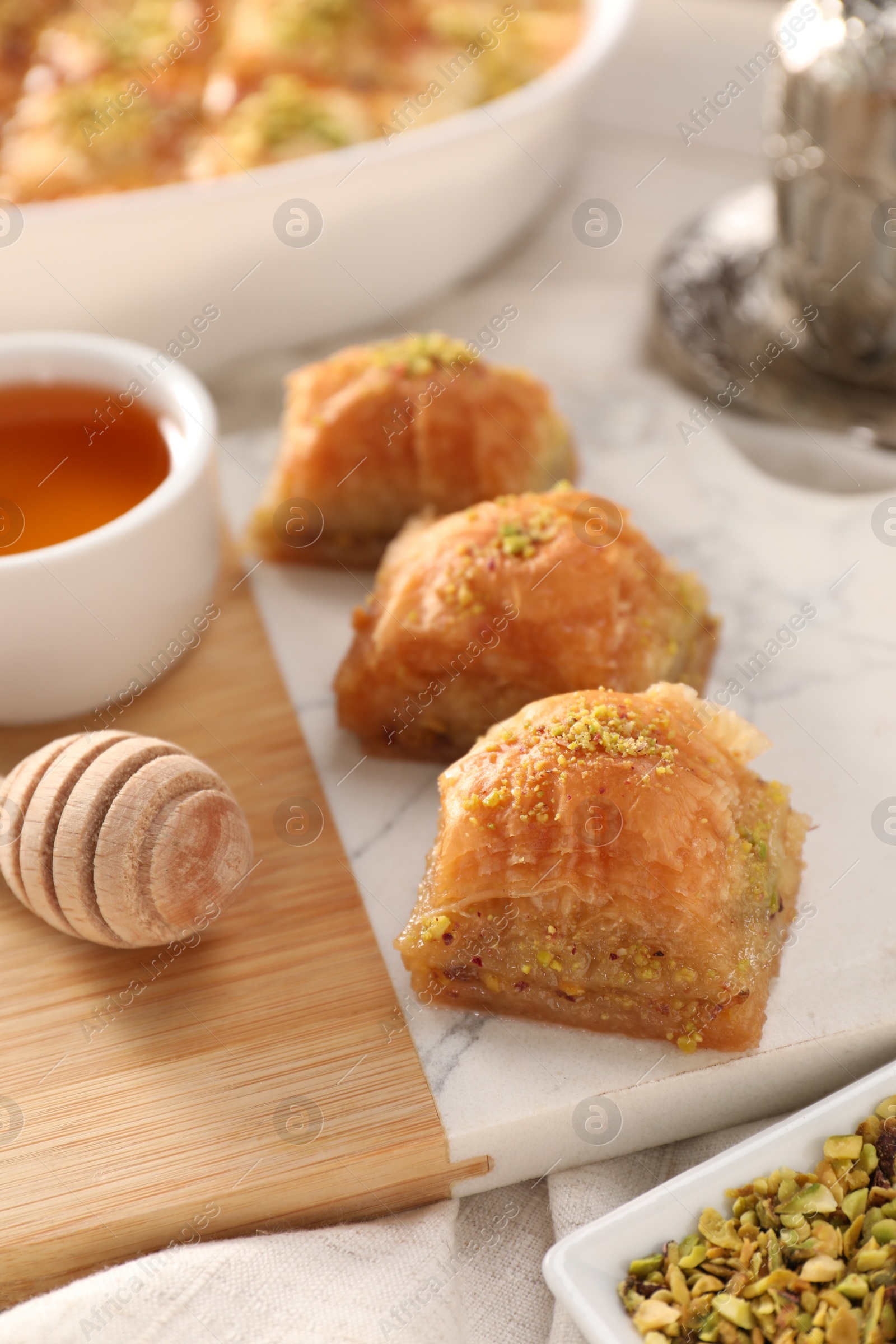 Photo of Delicious sweet baklava with pistachios and honey on table