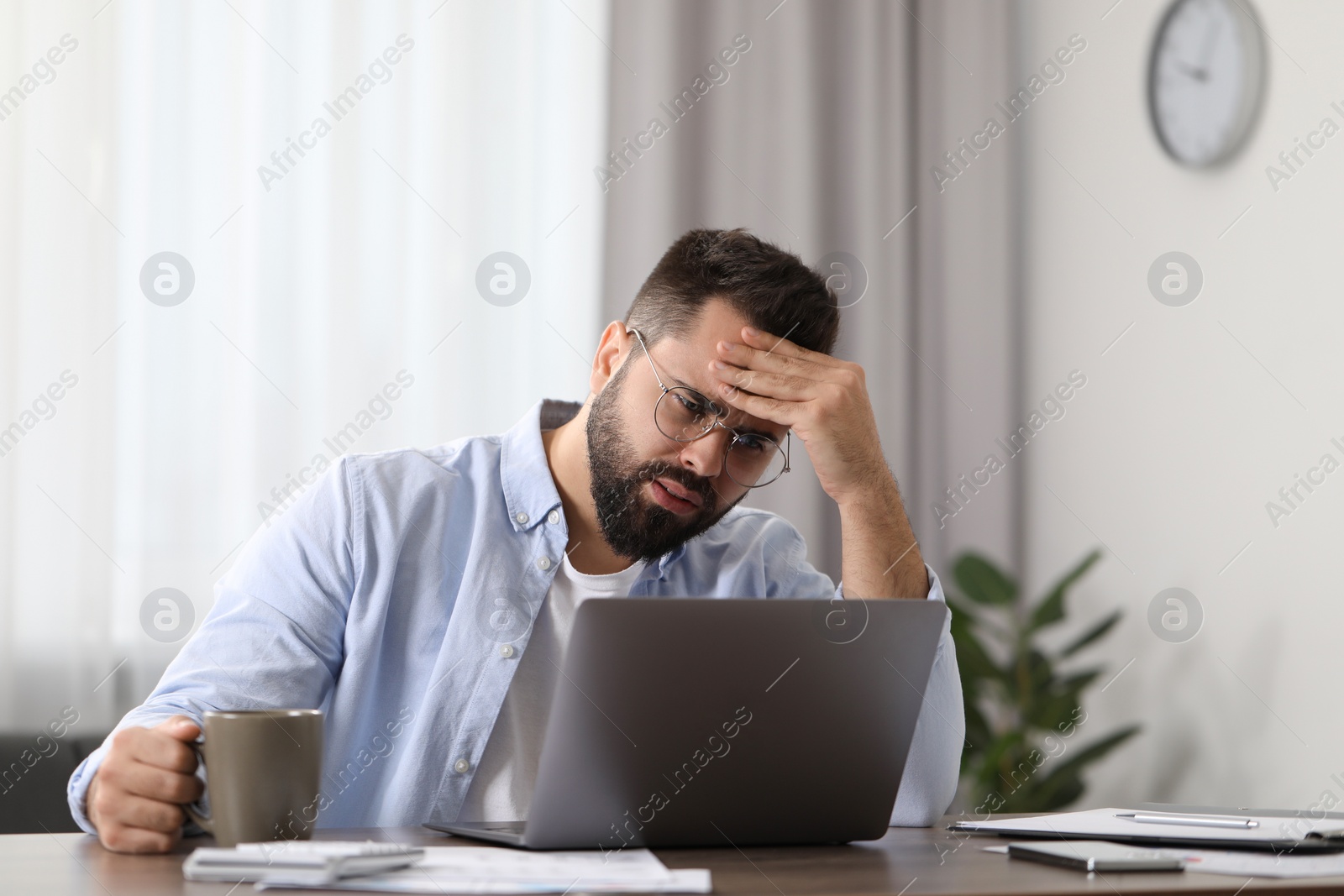 Photo of Man suffering from headache at workplace in office