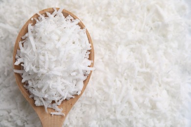 Fresh coconut flakes and wooden spoon, top view. Space for text