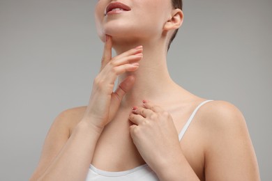 Photo of Woman touching her chin on grey background, closeup