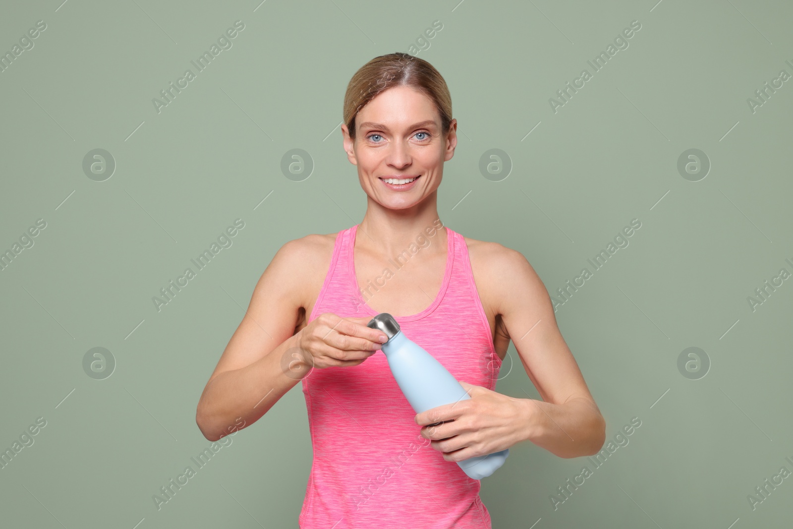 Photo of Sportswoman with thermo bottle on green background