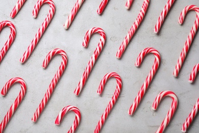 Photo of Sweet Christmas candy canes on grey background, flat lay