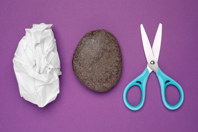 Photo of Rock, crumpled paper and scissors on purple background, flat lay