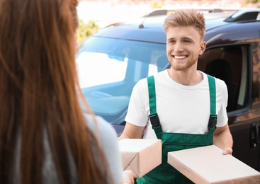 Young delivery courier giving parcels to customer outdoors