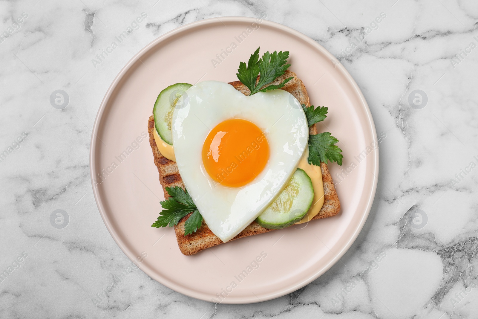 Photo of Plate of tasty sandwich with heart shaped fried egg on white marble table, top view