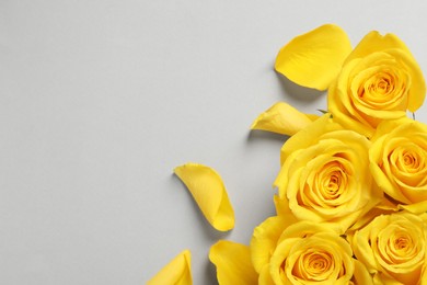 Photo of Beautiful yellow roses on light grey background, flat lay. Space for text