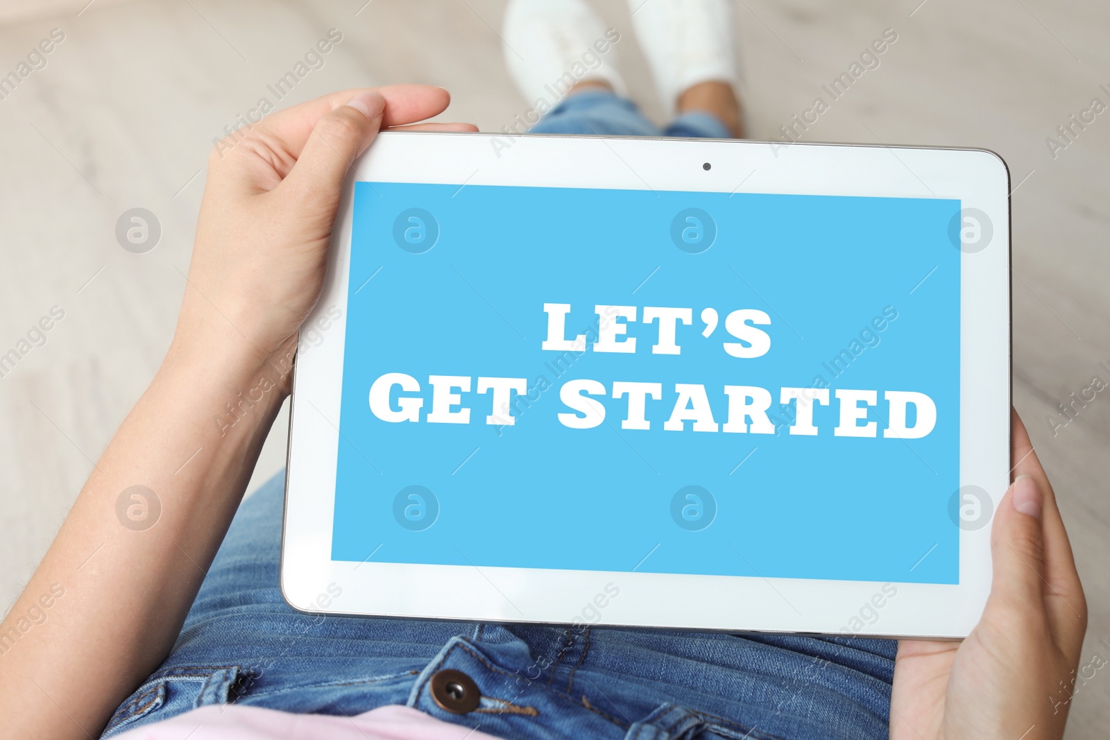 Image of Woman using tablet with phrase Let's Get Started indoors, closeup