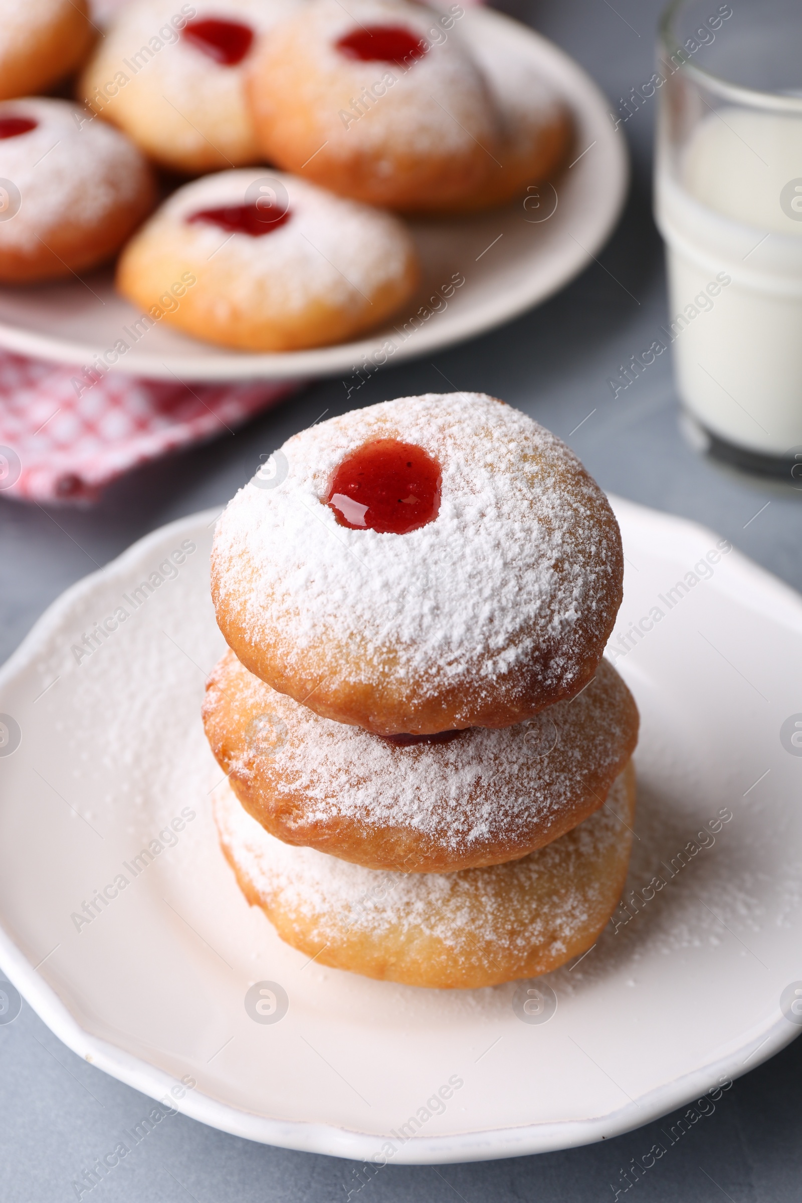 Photo of Hanukkah donuts with jelly and powdered sugar on light grey table