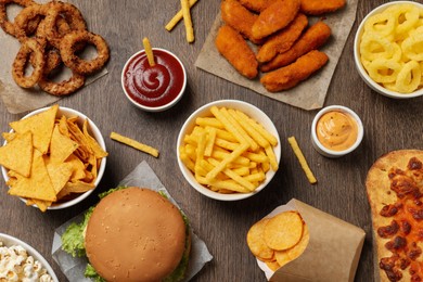 French fries, chips and other fast food on wooden table, flat lay