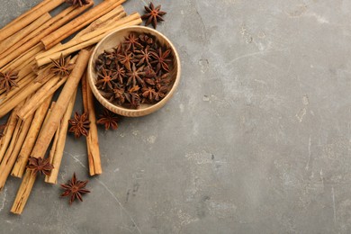 Photo of Aromatic cinnamon sticks and anise on grey table, flat lay. Space for text