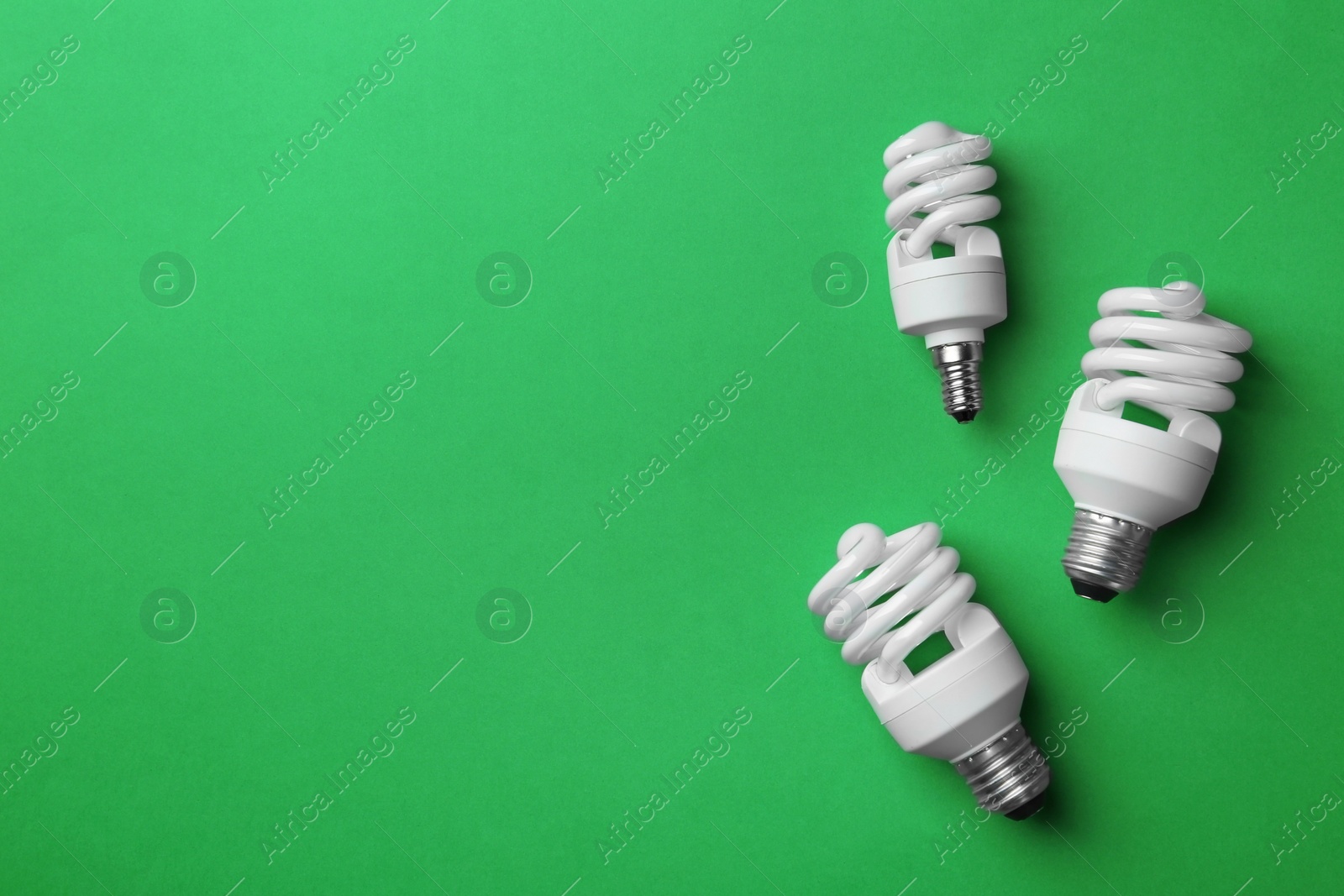 Photo of New fluorescent lamp bulbs on green background, top view. Space for text