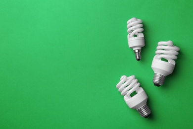 Photo of New fluorescent lamp bulbs on green background, top view. Space for text