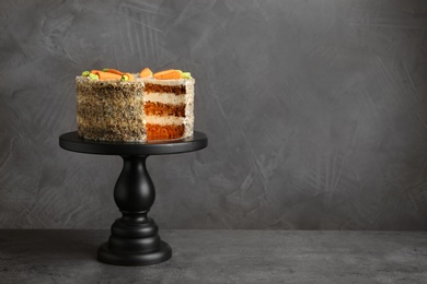 Photo of Stand with tasty carrot cake on grey table, space for text