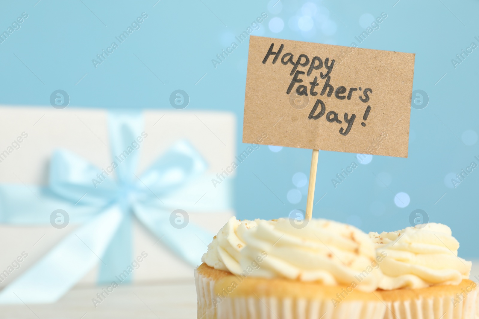 Photo of Happy Father's Day. Tasty cupcake with greetings on blurred background, closeup. Space for text