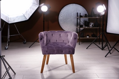 Interior of modern photo studio with armchair and professional equipment