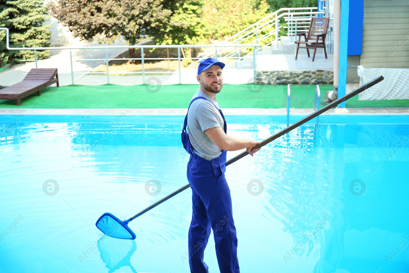 Photo of Male worker cleaning outdoor pool with scoop net