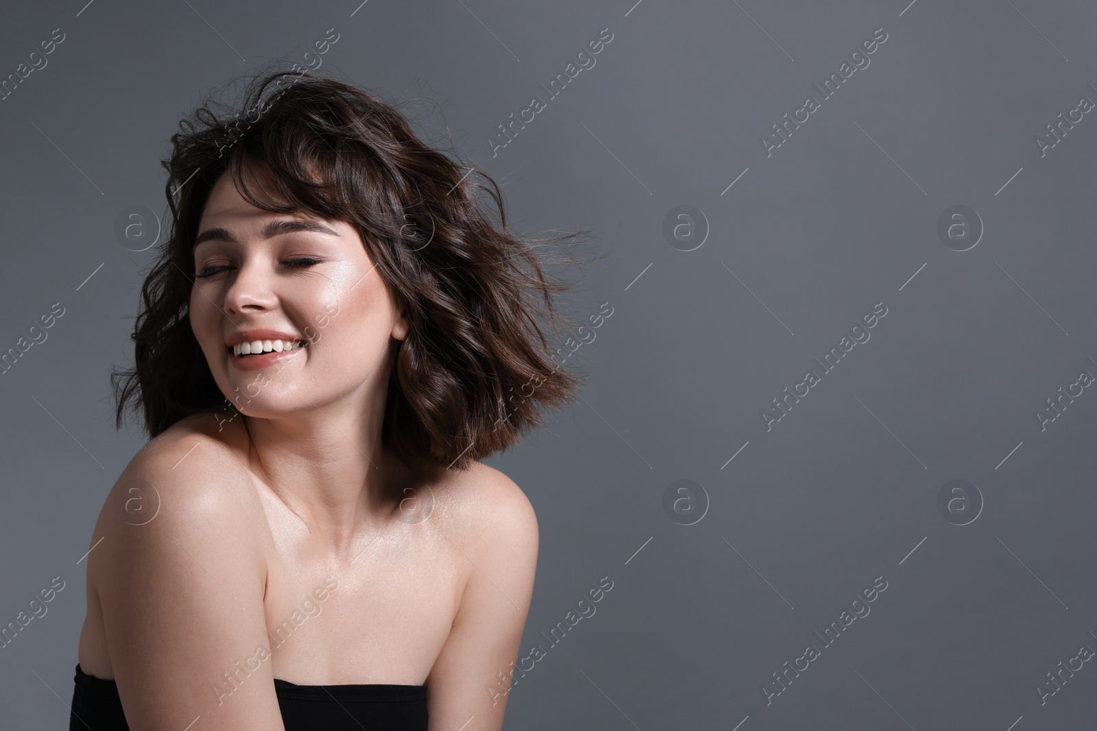 Photo of Portrait of beautiful young woman with wavy hairstyle on grey background. Space for text