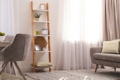 Photo of Stylish living room interior with wooden ladder near white wall