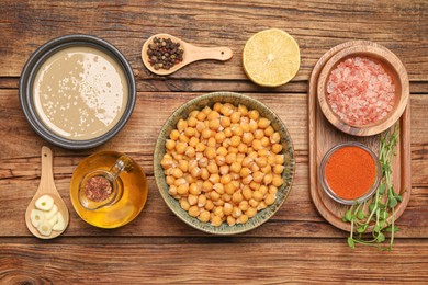 Photo of Delicious chickpeas and different products on wooden table, flat lay. Hummus ingredient