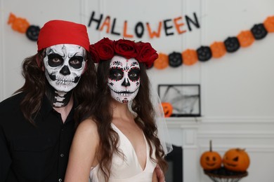 Photo of Couple in scary bride and pirate costumes indoors, space for text. Halloween celebration