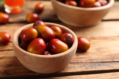 Photo of Palm oil fruits in bowl on wooden table, closeup