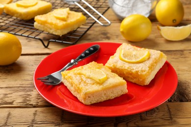 Photo of Tasty lemon bars and fork on wooden table, closeup