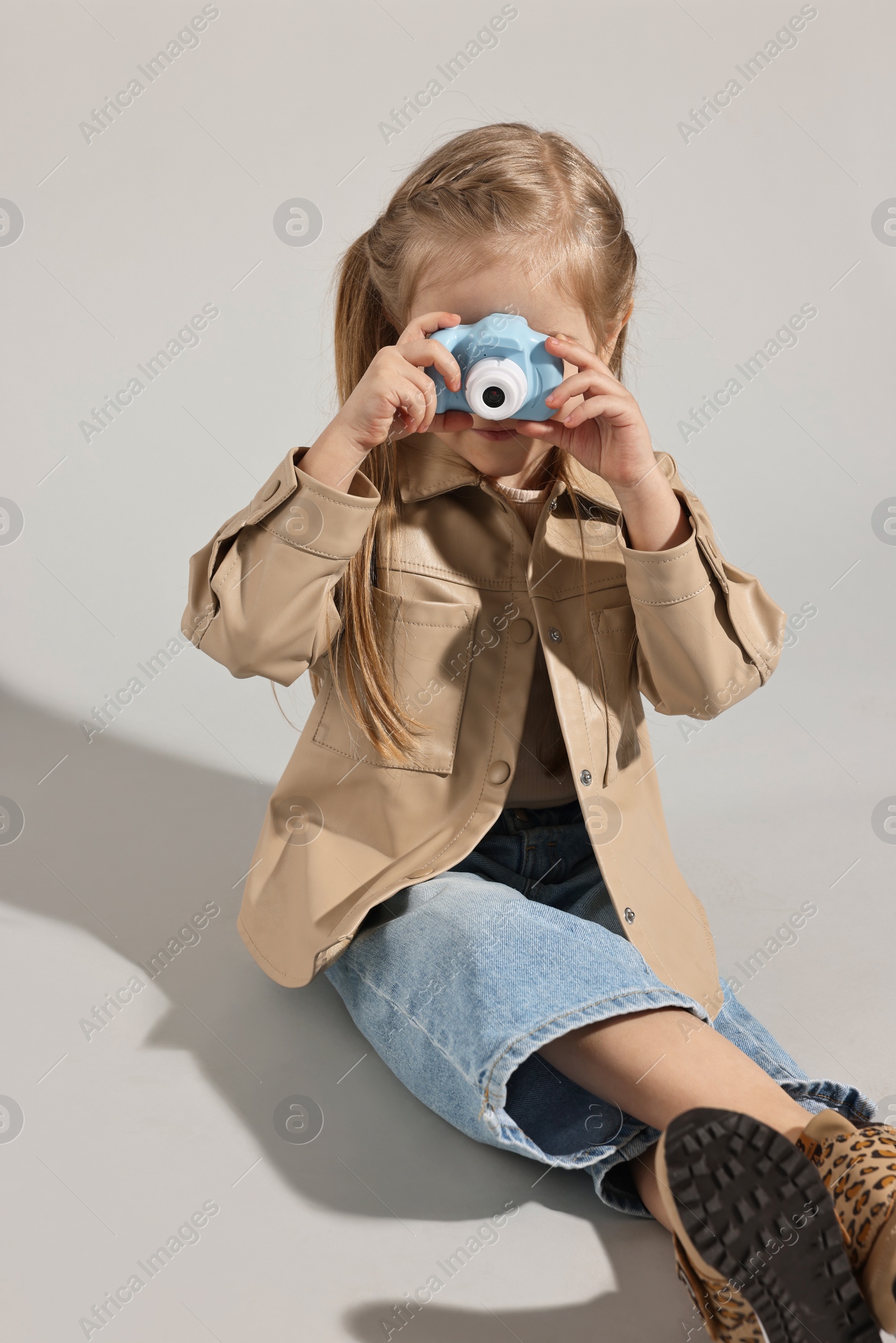 Photo of Fashion concept. Stylish girl with toy camera on light grey background