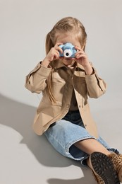 Fashion concept. Stylish girl with toy camera on light grey background