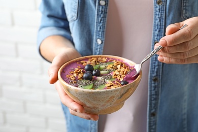 Woman eating acai smoothie with granola and berries, closeup