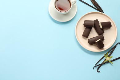 Photo of Glazed curd cheese bars, vanilla pods and tea on light blue background, flat lay. Space for text