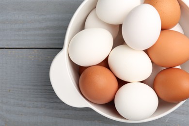 Photo of Unpeeled boiled eggs in saucepan on grey wooden table, top view. Space for text