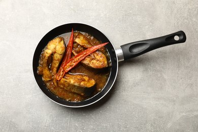 Photo of Tasty fish curry in frying pan on light grey table, top view. Indian cuisine