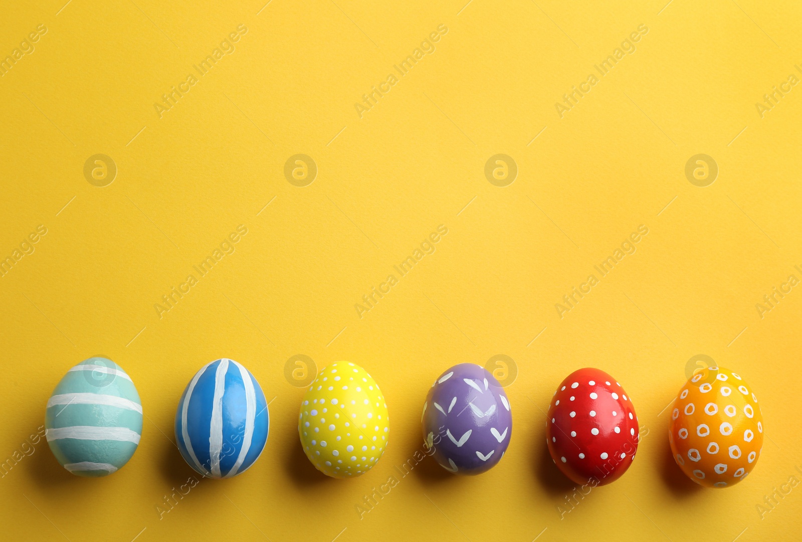 Photo of Flat lay composition of painted Easter eggs on color background, space for text